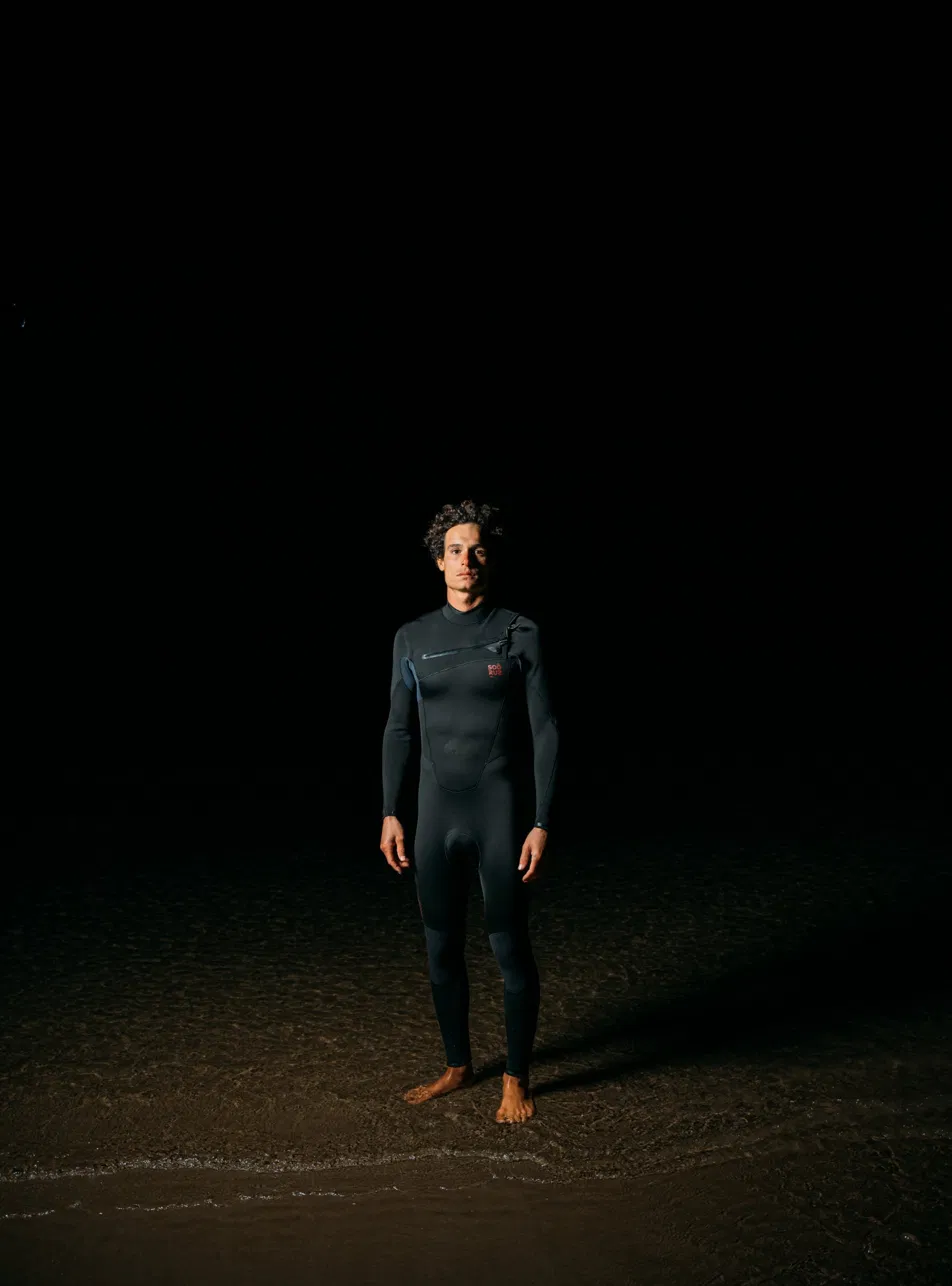 Rider wearing a Soöruz wetsuit on the beach at night