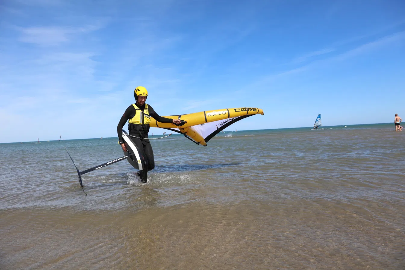 Wingfoil rider coming out of the water in a Soöruz vest and helmet